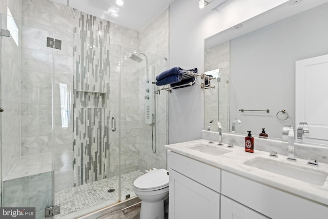 bathroom featuring walk in shower, dual sinks, toilet, and vanity with extensive cabinet space