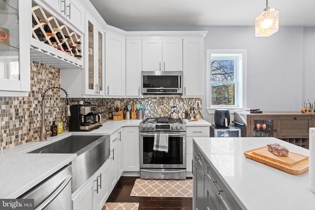 kitchen featuring decorative light fixtures, backsplash, stainless steel appliances, white cabinetry, and dark hardwood / wood-style flooring