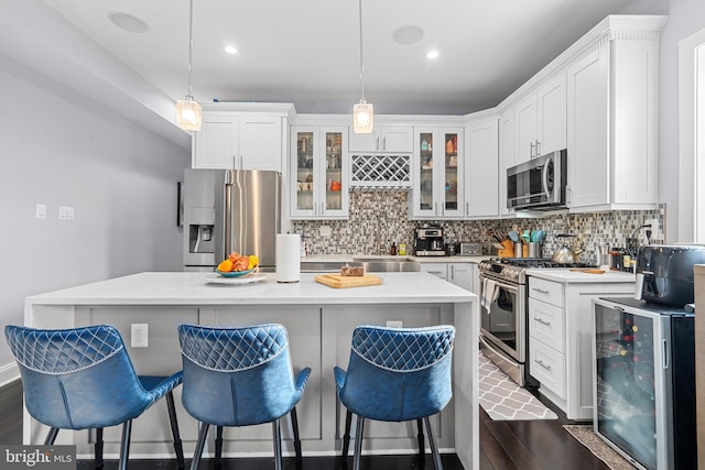 kitchen with white cabinets, beverage cooler, dark wood-type flooring, appliances with stainless steel finishes, and sink