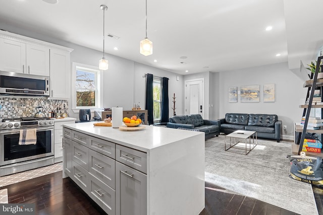 kitchen featuring decorative light fixtures, appliances with stainless steel finishes, tasteful backsplash, dark wood-type flooring, and white cabinets