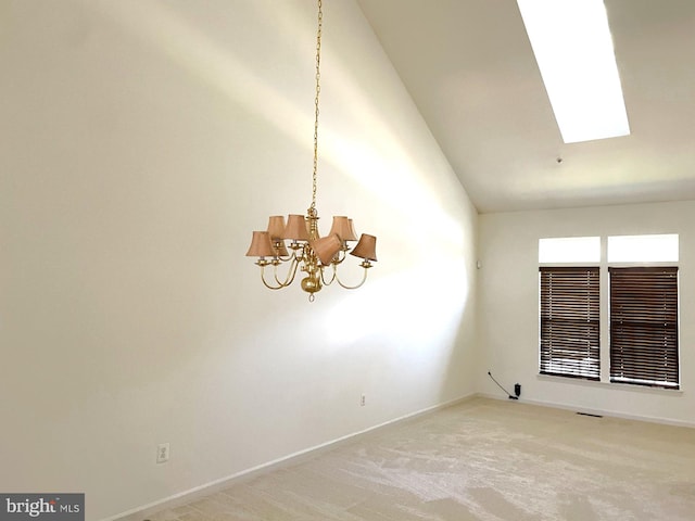 carpeted empty room with a notable chandelier, high vaulted ceiling, and a skylight