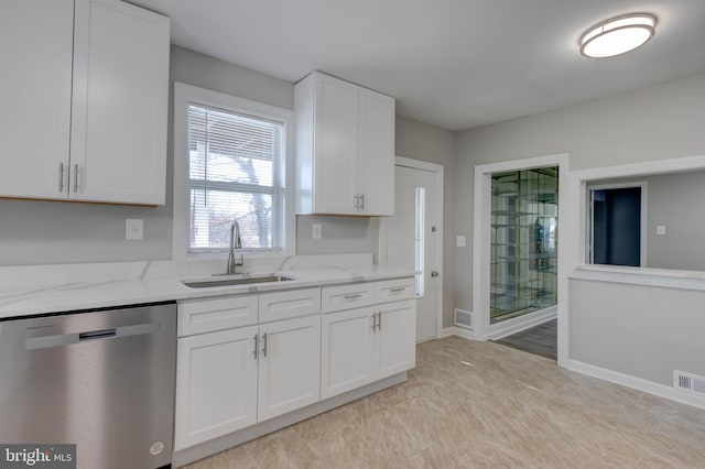 kitchen with light stone counters, dishwasher, white cabinets, and sink