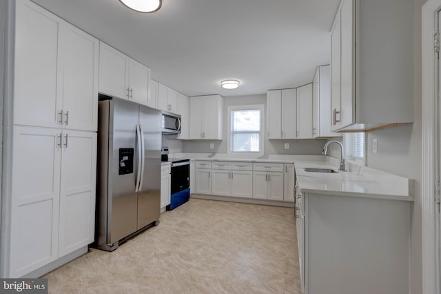 kitchen with white cabinetry, sink, light stone countertops, and appliances with stainless steel finishes