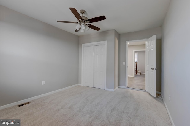 unfurnished bedroom featuring ceiling fan, light colored carpet, and a closet