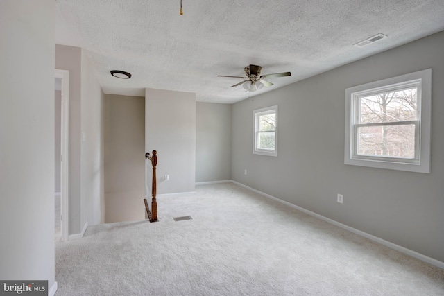 spare room with light carpet, ceiling fan, and a textured ceiling