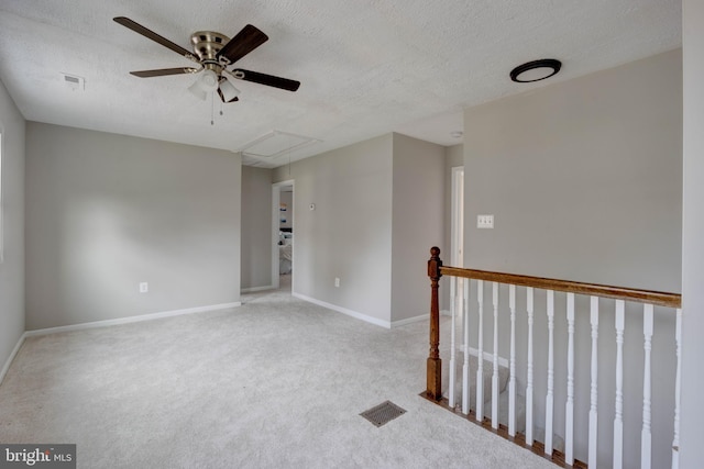 carpeted spare room with ceiling fan and a textured ceiling