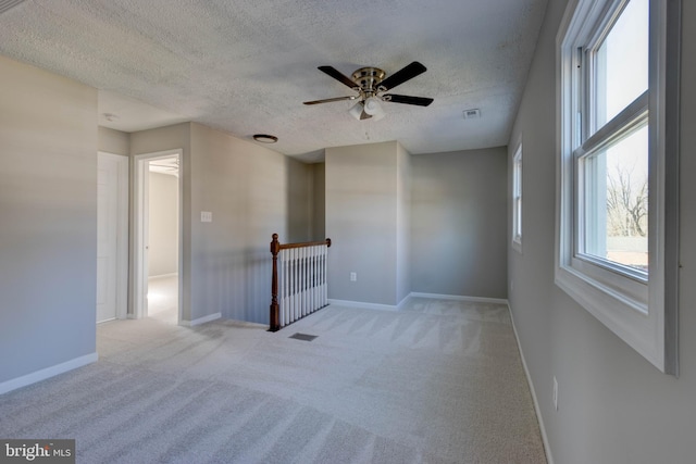 spare room with light carpet, a textured ceiling, and ceiling fan