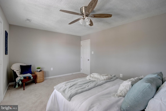 carpeted bedroom featuring ceiling fan and a textured ceiling