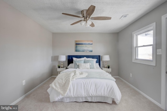 bedroom featuring ceiling fan, light carpet, and a textured ceiling