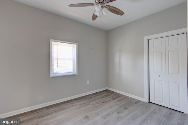 unfurnished bedroom featuring ceiling fan, a closet, and light wood-type flooring