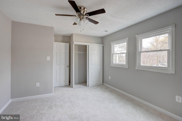 unfurnished bedroom with light carpet, a textured ceiling, a closet, and ceiling fan