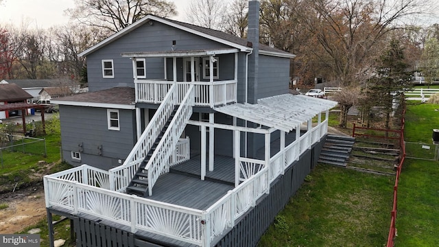 rear view of house featuring a yard, a sunroom, and a wooden deck