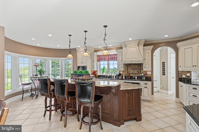 kitchen featuring a wealth of natural light, tasteful backsplash, custom exhaust hood, and a kitchen island