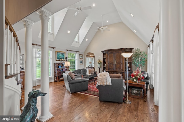 living room featuring high vaulted ceiling, light hardwood / wood-style floors, ceiling fan, and decorative columns