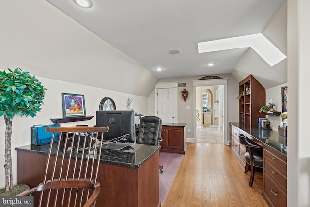 home office featuring light hardwood / wood-style flooring and vaulted ceiling with skylight