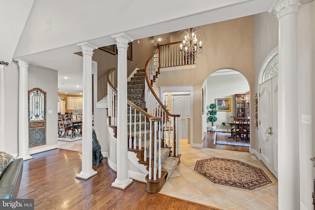 foyer featuring ornate columns, a towering ceiling, and a notable chandelier