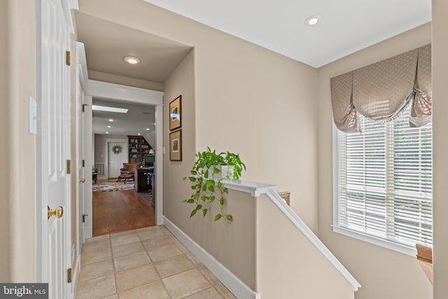 hallway with an inviting chandelier and light tile floors