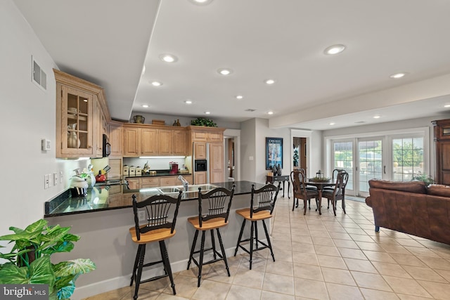 kitchen featuring paneled refrigerator, a breakfast bar, kitchen peninsula, sink, and light tile floors