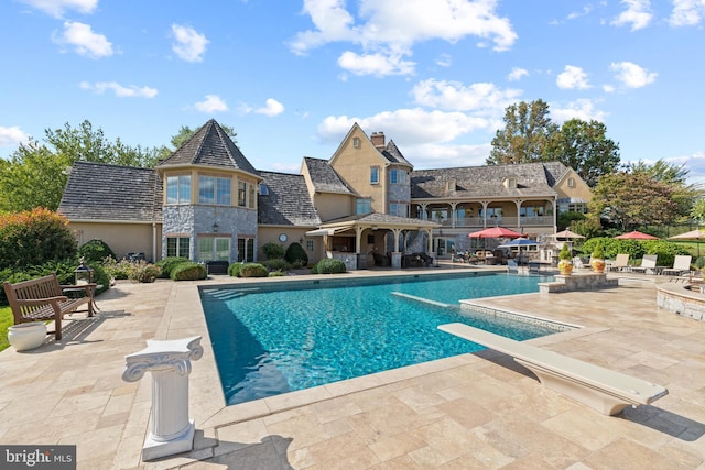 view of swimming pool featuring a patio area and a diving board