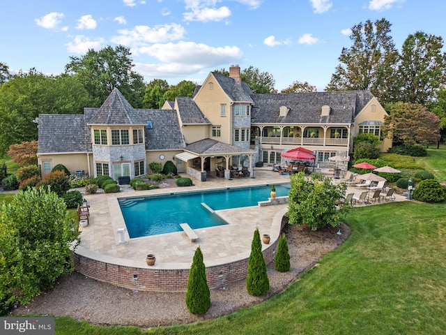 view of pool with a lawn, a diving board, and a patio