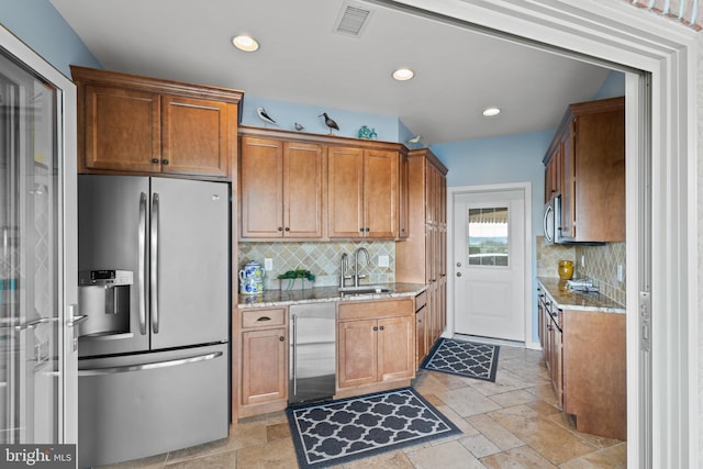 kitchen with appliances with stainless steel finishes, light stone countertops, backsplash, and light tile floors