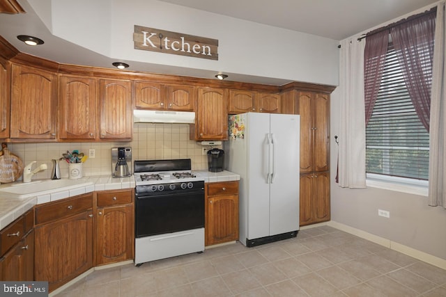 kitchen with sink, tile countertops, white appliances, decorative backsplash, and light tile patterned floors