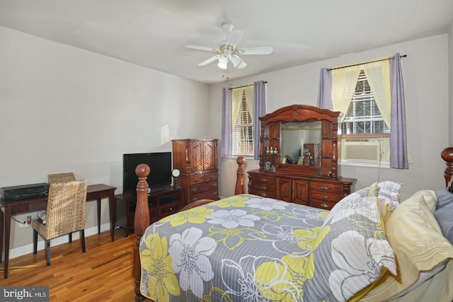 bedroom with multiple windows, ceiling fan, cooling unit, and wood-type flooring