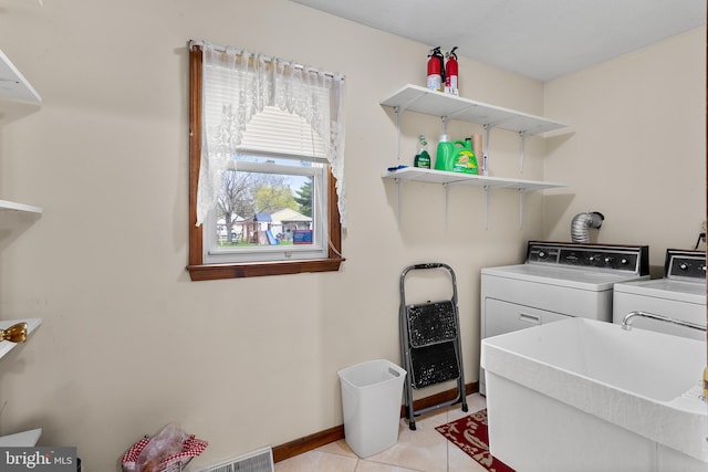 washroom featuring sink, washing machine and dryer, and light tile floors