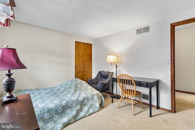 bedroom with a textured ceiling and light carpet