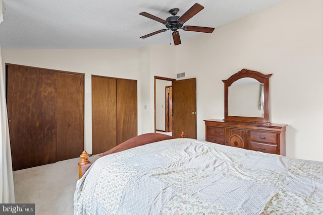 carpeted bedroom featuring vaulted ceiling, ceiling fan, and two closets