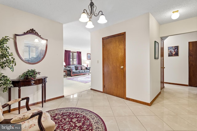 hallway featuring light colored carpet, an inviting chandelier, and a textured ceiling