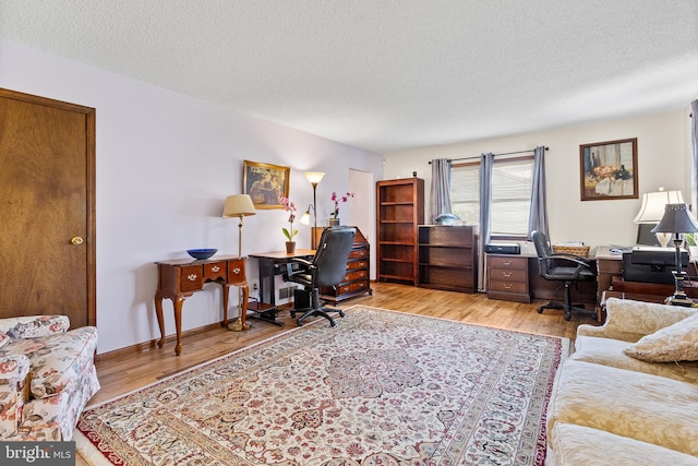 home office featuring light hardwood / wood-style floors and a textured ceiling