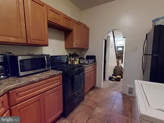 kitchen with stainless steel appliances, washer / dryer, and light tile floors