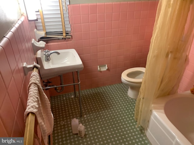 full bathroom with shower / bath combination with curtain, tile floors, tile walls, sink, and toilet