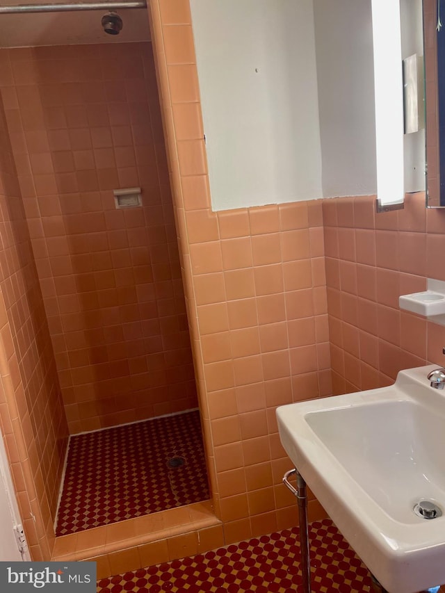 bathroom with tile flooring, tile walls, sink, and a tile shower