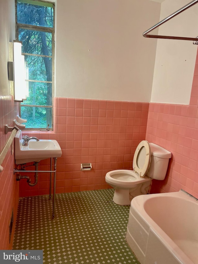 bathroom with tile floors, tile walls, sink, and toilet