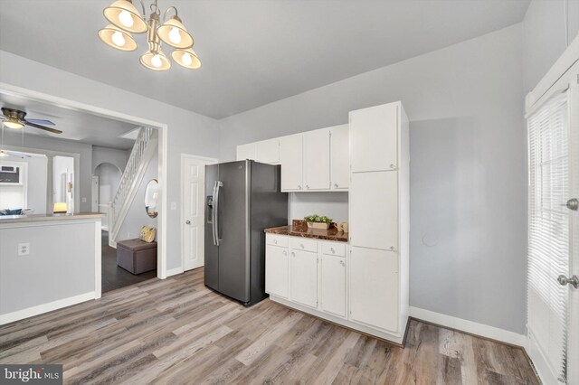 kitchen featuring ceiling fan with notable chandelier, stainless steel fridge with ice dispenser, light hardwood / wood-style flooring, and white cabinetry