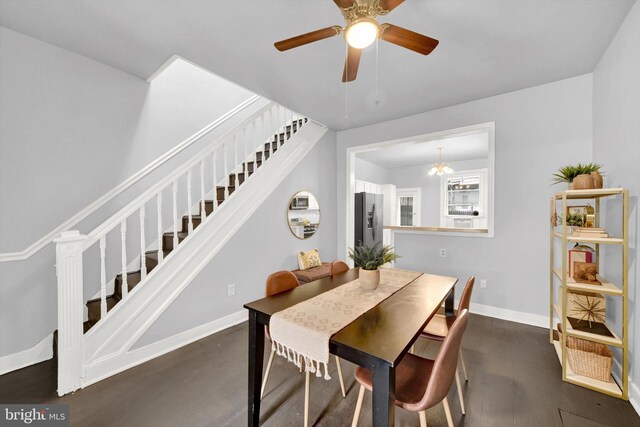 dining area with ceiling fan with notable chandelier and dark hardwood / wood-style flooring