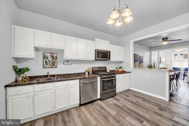 kitchen featuring appliances with stainless steel finishes, light hardwood / wood-style floors, white cabinets, and decorative light fixtures