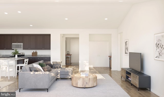 living room featuring lofted ceiling, light wood-type flooring, and recessed lighting