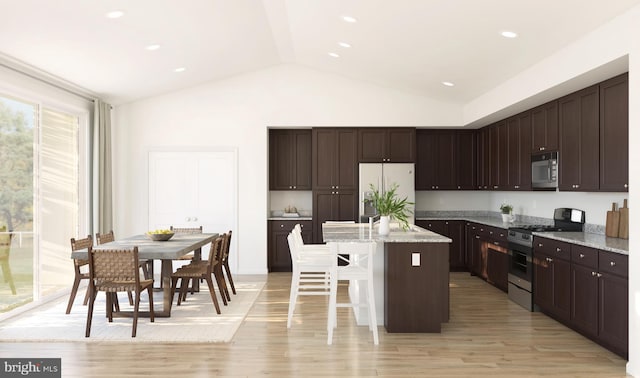 kitchen with light stone countertops, a breakfast bar area, stainless steel appliances, a center island with sink, and lofted ceiling