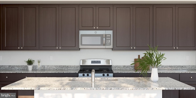 kitchen featuring light stone counters, stainless steel appliances, and dark brown cabinets