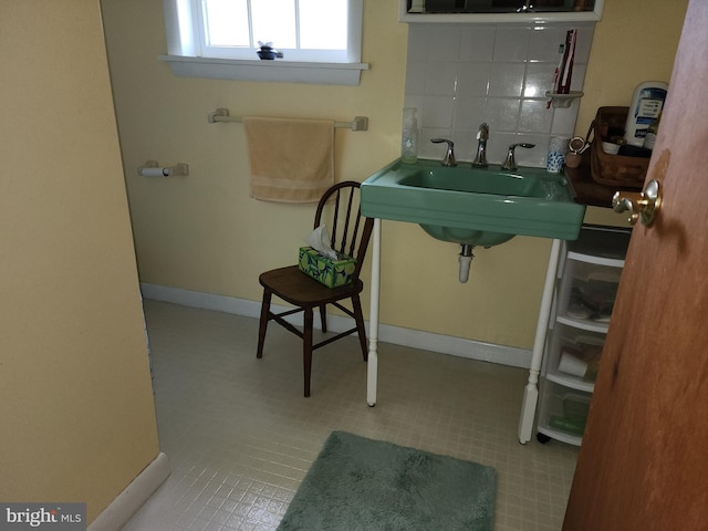 bathroom with tasteful backsplash, tile floors, and sink