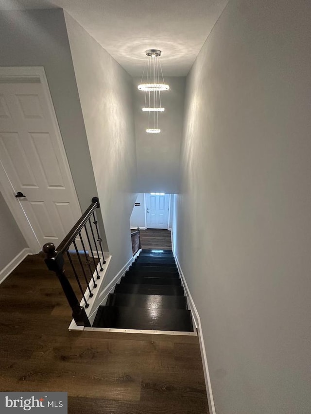 stairway featuring hardwood / wood-style flooring and a chandelier