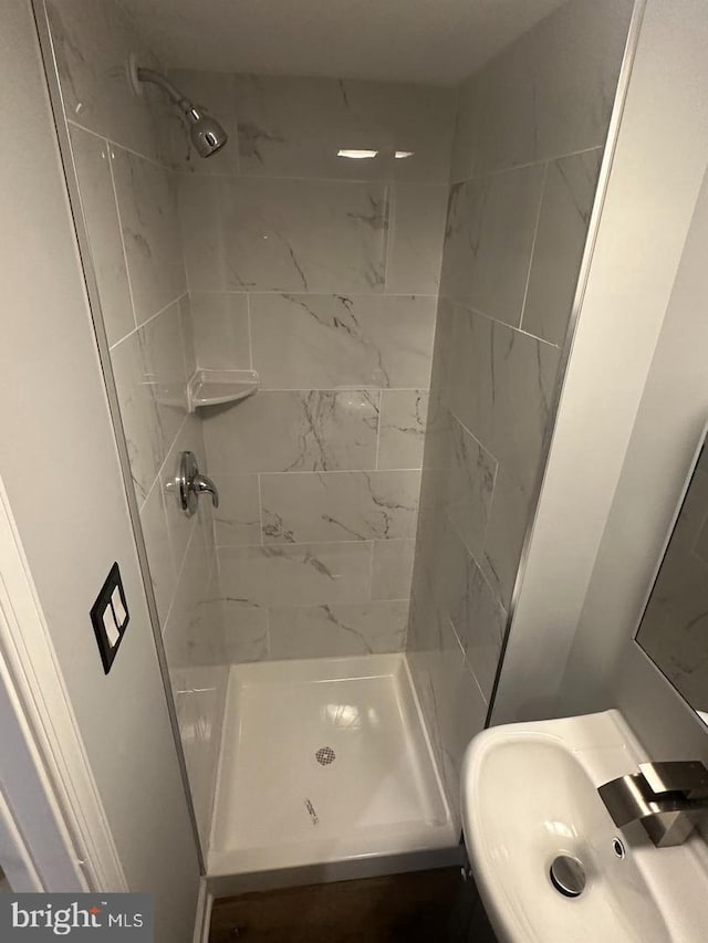 bathroom featuring a tile shower and sink