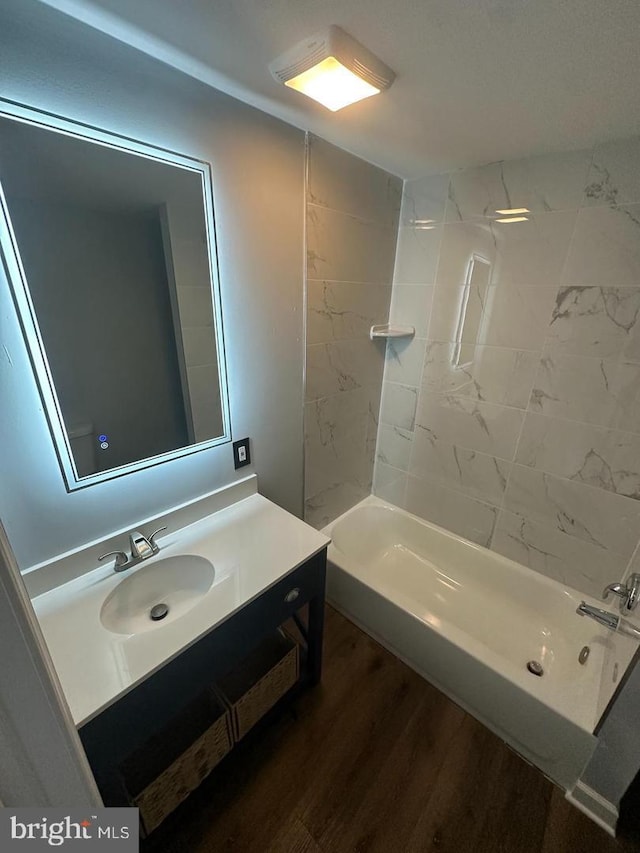 bathroom with tiled shower / bath combo, wood-type flooring, and vanity