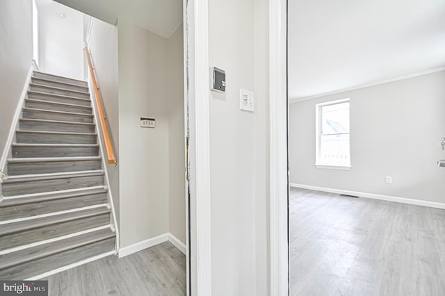 stairway featuring crown molding and light wood-type flooring