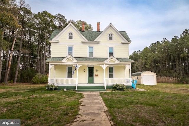 view of front of house with a front lawn, an outdoor structure, a garage, and covered porch