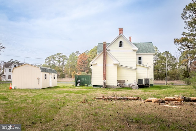 rear view of house with a shed and a lawn