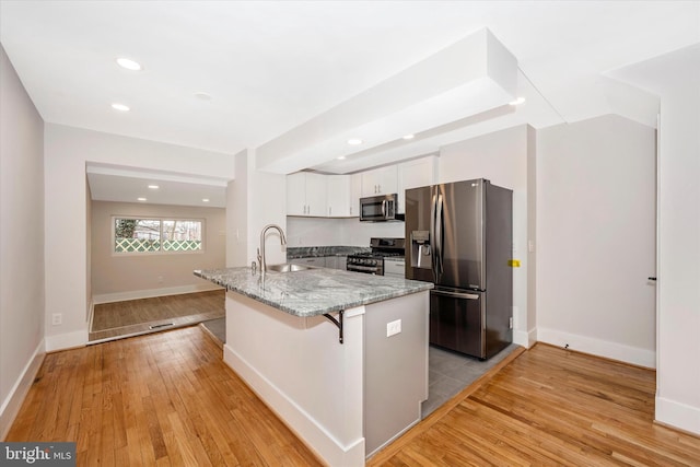 kitchen with white cabinets, appliances with stainless steel finishes, sink, and light hardwood / wood-style floors